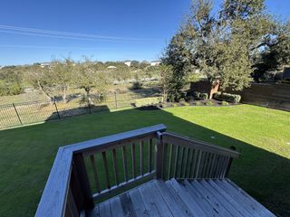 A beautiful backyard with lush grass and a wooden deck in Provence 70s by Ashton Woods (Austin, TX).
