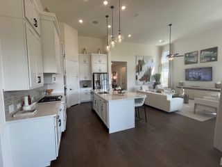A bright and open kitchen with white cabinetry, quartz countertops, and stylish pendant lighting.