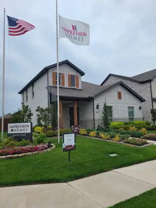 Charming brick home with wooden shutters and lush landscaping in Bryant Farms by Impression Homes (Melissa, TX).