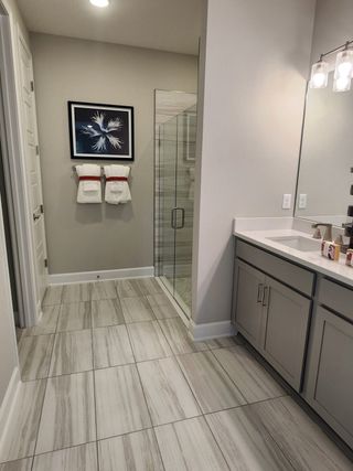 A modern bathroom featuring a glass shower, elegant tile flooring, sleek cabinetry, and artistic wall decor.