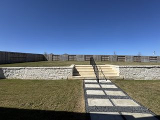 A neatly landscaped backyard with stone steps and fenced privacy in Homestead by Coventry Homes (Schertz, TX).