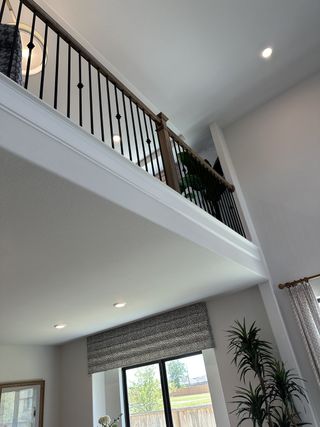 Model Home A modern living area featuring high ceilings, a sleek iron railing, and large windows for ample natural light.