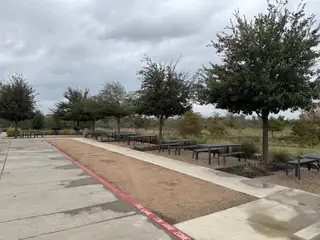 A peaceful park area with picnic tables and lush trees in Urban Courtyard Homes at Easton Park by Brookfield Residential, Austin, TX.