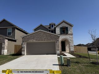Street view A charming brick home with a two-car garage in Presidential Meadows by KB Home (Manor, TX).