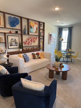 Model Home A vibrant living room with eclectic art, cozy seating, and a stylish table, creating an inviting and modern atmosphere.
