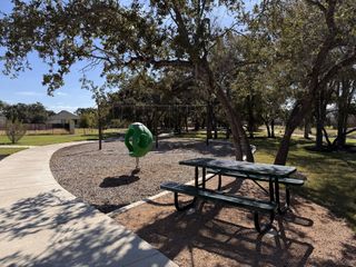A serene park with a playground and picnic table in Highland Village by Coventry Homes (Georgetown, TX).