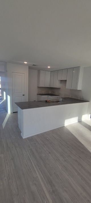 Model Home A modern kitchen with sleek white cabinets, a dark island, and natural light streaming through large windows.
