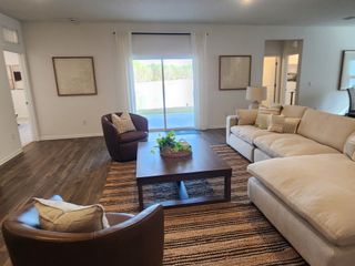 A cozy living room with plush seating, wood flooring, and a view through sliding glass doors to a serene outdoor space.