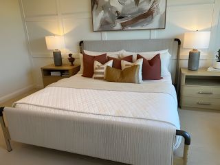 A cozy bedroom with a modern upholstered bed, warm tones, stylish artwork, and elegant lighting.