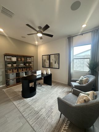 Model Home A modern home office with sleek furnishings, cozy chairs, and ample natural light flooding through a large window.