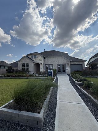 A beautiful stone home with a well-manicured lawn in Arabella on the Prairie by Pulte Homes (Richmond, TX).