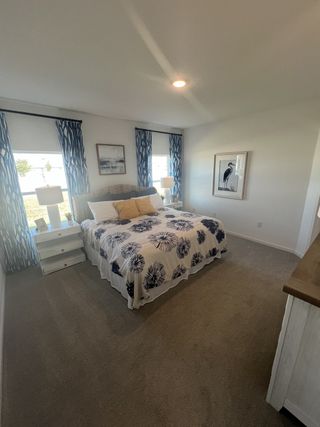 A cozy bedroom with patterned bedding, elegant blue curtains, and tasteful artwork for a serene retreat.