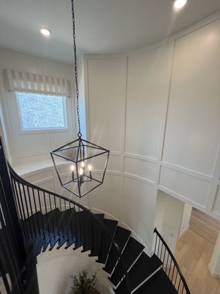 A grand entryway with a curved staircase and modern chandelier in Solterra Texas by Shaddock Homes (Mesquite, TX).