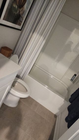 A cozy bathroom with a fresh green accent wall, a white vanity, and a relaxing bathtub with a striped curtain.