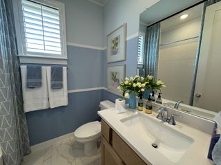 A chic bathroom with blue walls, tasteful decor, and a sleek vanity paired with modern fixtures.
