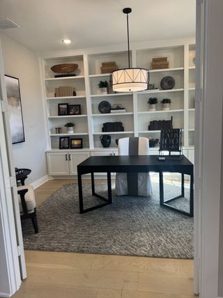 A sophisticated home office with a modern black desk, built-in bookshelves, and elegant pendant lighting.