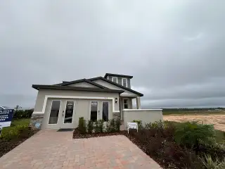 A modern home with large windows and a paved driveway in Springs at Lake Alfred - Classic Series by Meritage Homes (Lake Alfred, FL).