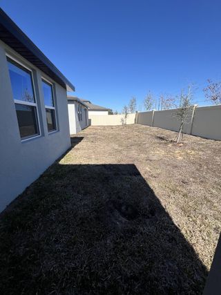 A spacious backyard with privacy fencing and a modern exterior in Bradbury Creek - Signature Series by Meritage Homes (Haines City, FL).
