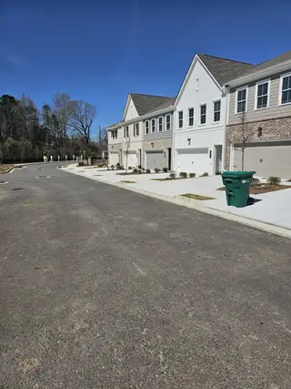 A row of elegant townhomes with brick facades in River Walk Place by Traton Homes (Lawrenceville, GA).