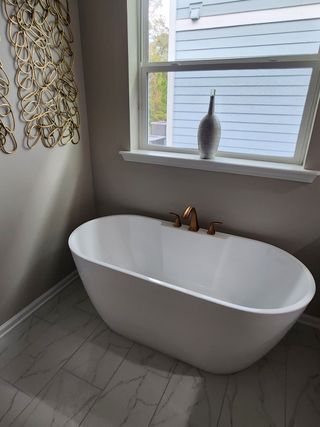 A modern bathroom with a sleek freestanding tub, elegant brass fixtures, and decorative wall art.