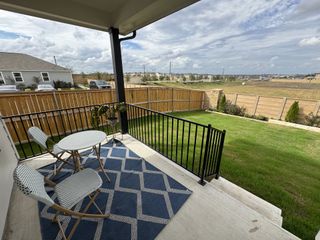 Model Home A cozy patio with patterned seating and a scenic view of a lush fenced yard, perfect for relaxing and enjoying the outdoors.