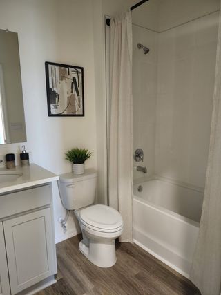 A modern bathroom with a sleek white bathtub, light wood flooring, and minimalistic décor.