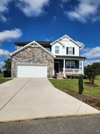 Street view A charming two-story home with brick accents and a spacious driveway in Hawthorne West by Lennar (Zebulon, NC).