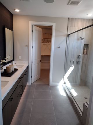 A modern bathroom featuring a spacious glass shower, dual sinks, and sleek cabinetry with elegant finishes.