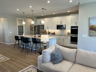Model Home A modern kitchen with elegant pendant lighting, sleek appliances, and a cozy open-concept seating area.