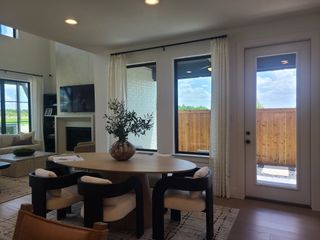 A modern living area with a cozy round table, stylish chairs, and large windows offering abundant natural light.