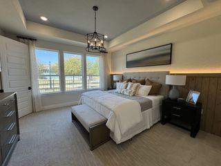 A serene bedroom featuring a king-sized bed, modern lighting, and large windows offering abundant natural light.