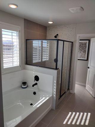 A modern bathroom featuring a sleek bathtub, glass shower, and elegant tile accents with abundant natural light.