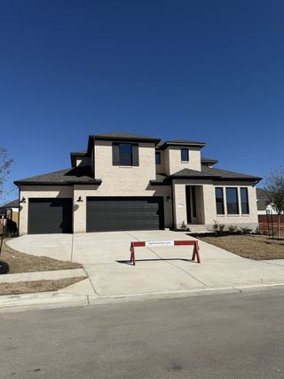 Street view Elegant two-story home with dark accents and triple garage in Santa Rita Ranch by Taylor Morrison, Liberty Hill, TX.