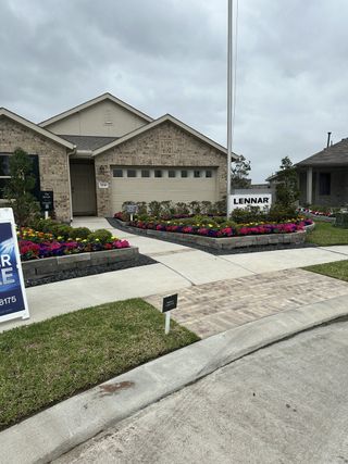 Street view A charming brick home with vibrant landscaping in Tavola by Lennar (New Caney, TX).
