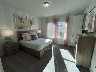 A cozy bedroom featuring stylish decor, soft lighting, and a modern dresser with large windows for natural light.