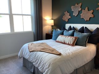 A modern bedroom featuring a blue accent wall, abstract decor, plush bedding, and warm ambient lighting.