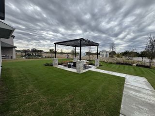 Street view A modern pergola in a lush garden at Santa Rita Ranch by Chesmar Homes, Liberty Hill, TX.