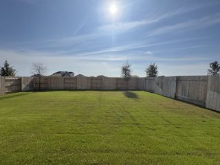 Expansive, sunlit fenced backyard with manicured lawn in Nolina - 60' by Westin Homes (Georgetown, TX).