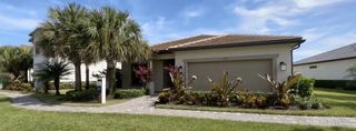 A charming beige home with palm trees and manicured landscaping in Oak Tree by Pulte Homes (Oakland Park, FL).