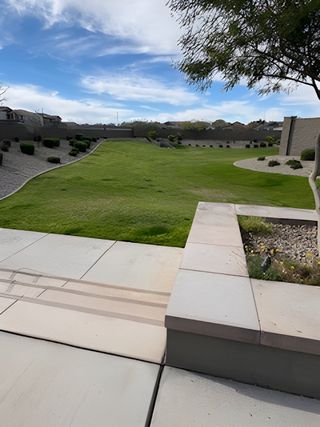 Community Amenities A paved patio overlooks a lush green yard with desert landscaping in Redwood Valley at Escalante by Fulton Homes (Surprise, AZ).