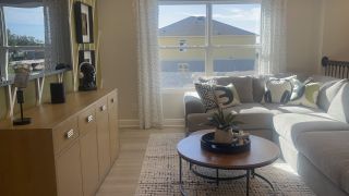 Model Home A cozy living room with a modern grey sectional, chic decor, and natural light streaming through large windows.