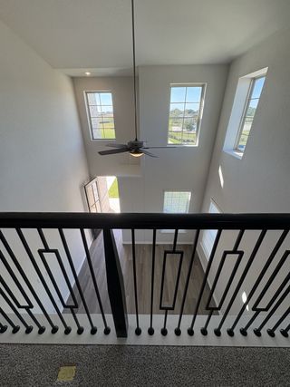 An elegant staircase landing with stylish black iron railings overlooking the open-concept living area below.