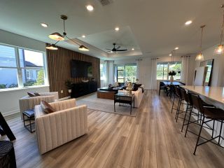 Model Home A beautifully designed open-concept living area with warm wood tones, stylish lighting, and large windows that bring in natural light.