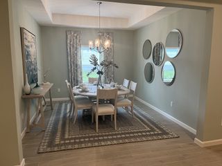 A chic dining room with round mirrors, elegant chandelier, and a patterned rug complementing the soft gray walls.
