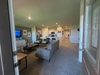 A spacious open-concept living room and kitchen with modern furnishings and subtle green accents.