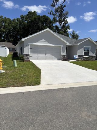 Street view A modern home with a clean facade and spacious driveway in Bennah Oaks by Highland Homes of Florida (Belleview, FL).