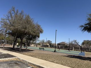 Model Home A vibrant basketball court surrounded by trees in Stillwater Ranch by Coventry Homes (San Antonio, TX).