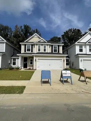 Street view A beautiful two-story home with a manicured lawn in Hampton Woods by Dream Finders Homes (Summerville, SC).
