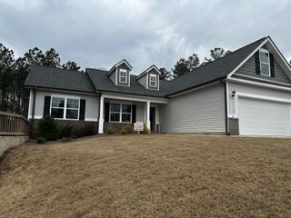 A modern farmhouse-style home with dormer windows and a two-car garage in Covington by Castle Homes (Savoy Park, GA).
