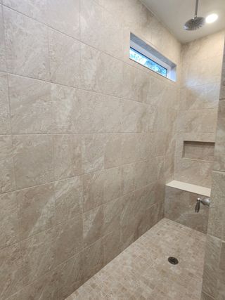 Model Home A spacious walk-in shower with floor-to-ceiling beige tiles and a rainfall showerhead.